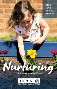 A young girl wearing a white shirt with colorful flowers leans over a blue planter box, tending to yellow and red flowers. The text reads 2024 JCYS Annual Report: Nurturing the Next Generation..